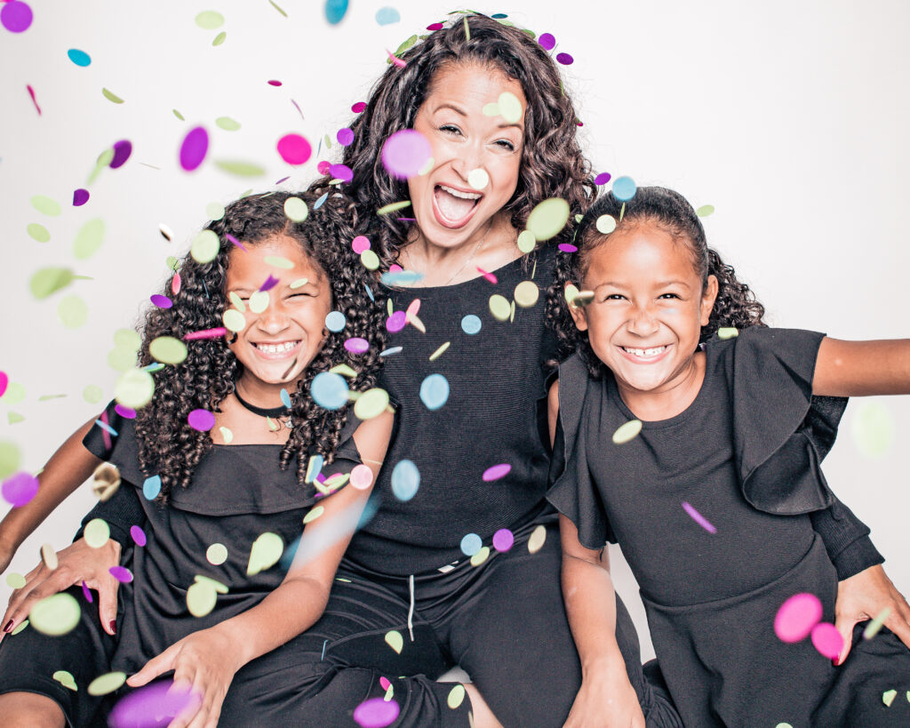 Three joyful kids celebrating with colorful confetti.