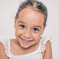 Smiling young girl in a white dress with braided hair.