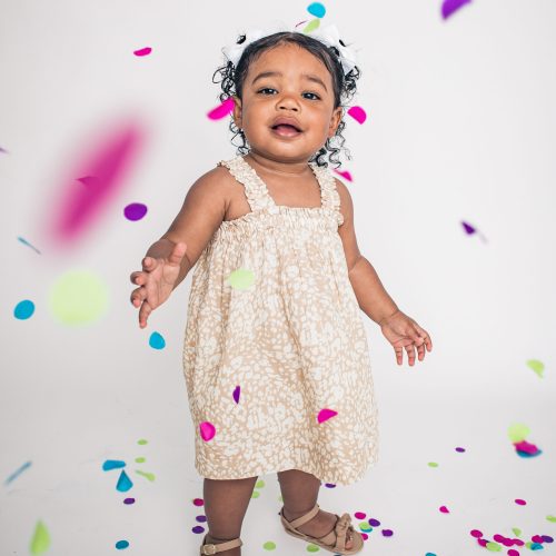 Happy toddler playing joyfully with colorful confetti.